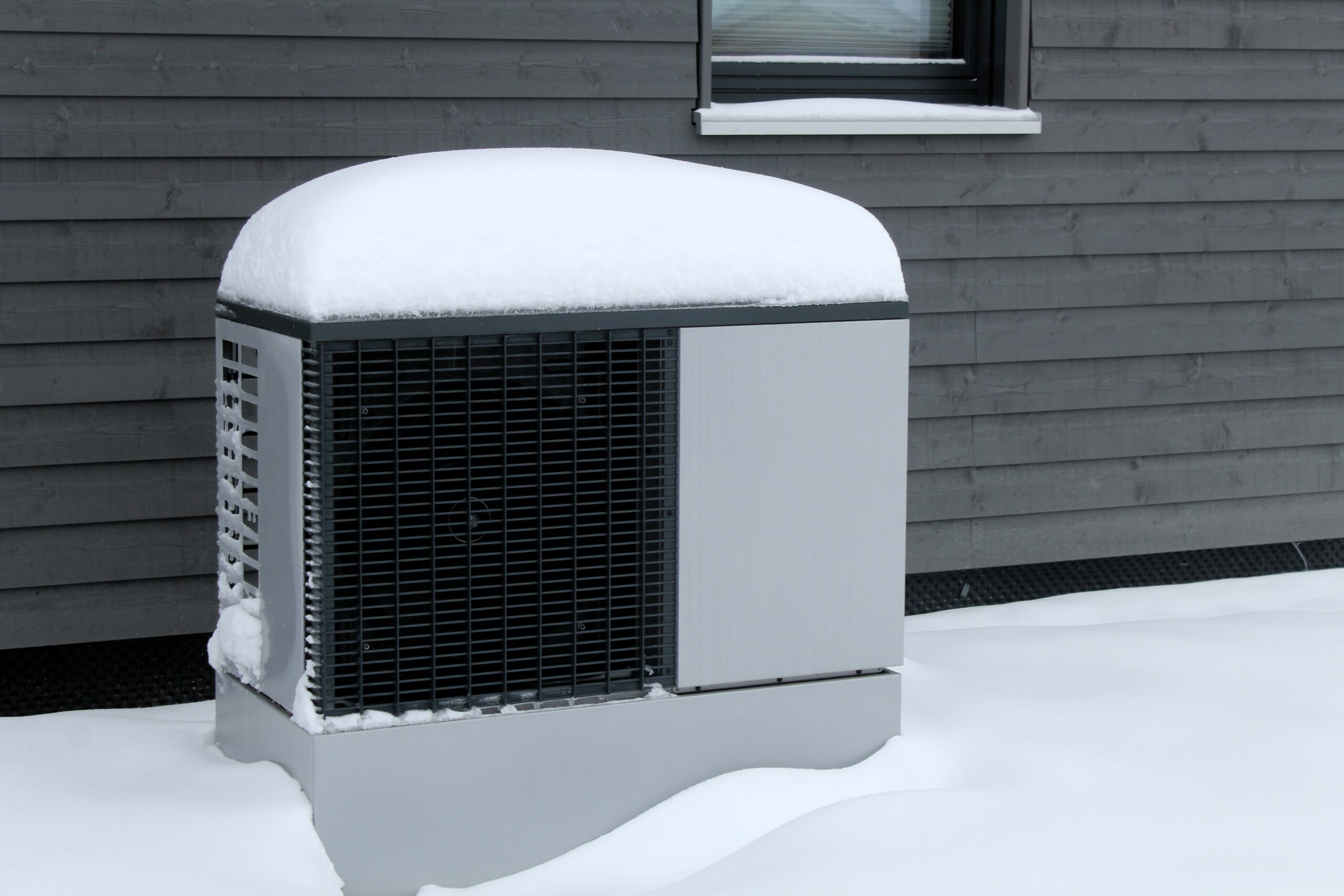 Vereiste Wärmepumpe steht an der Hauswand im Schnee