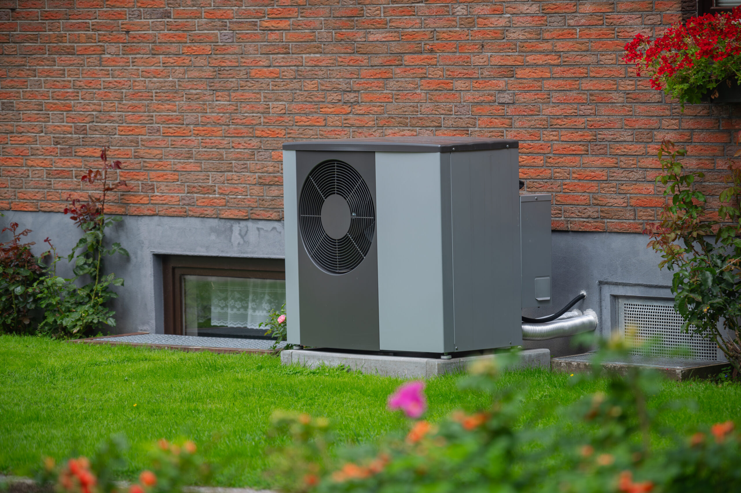 Ein Wärmepumpen-Außengerät im Garten nahe der Hauswand