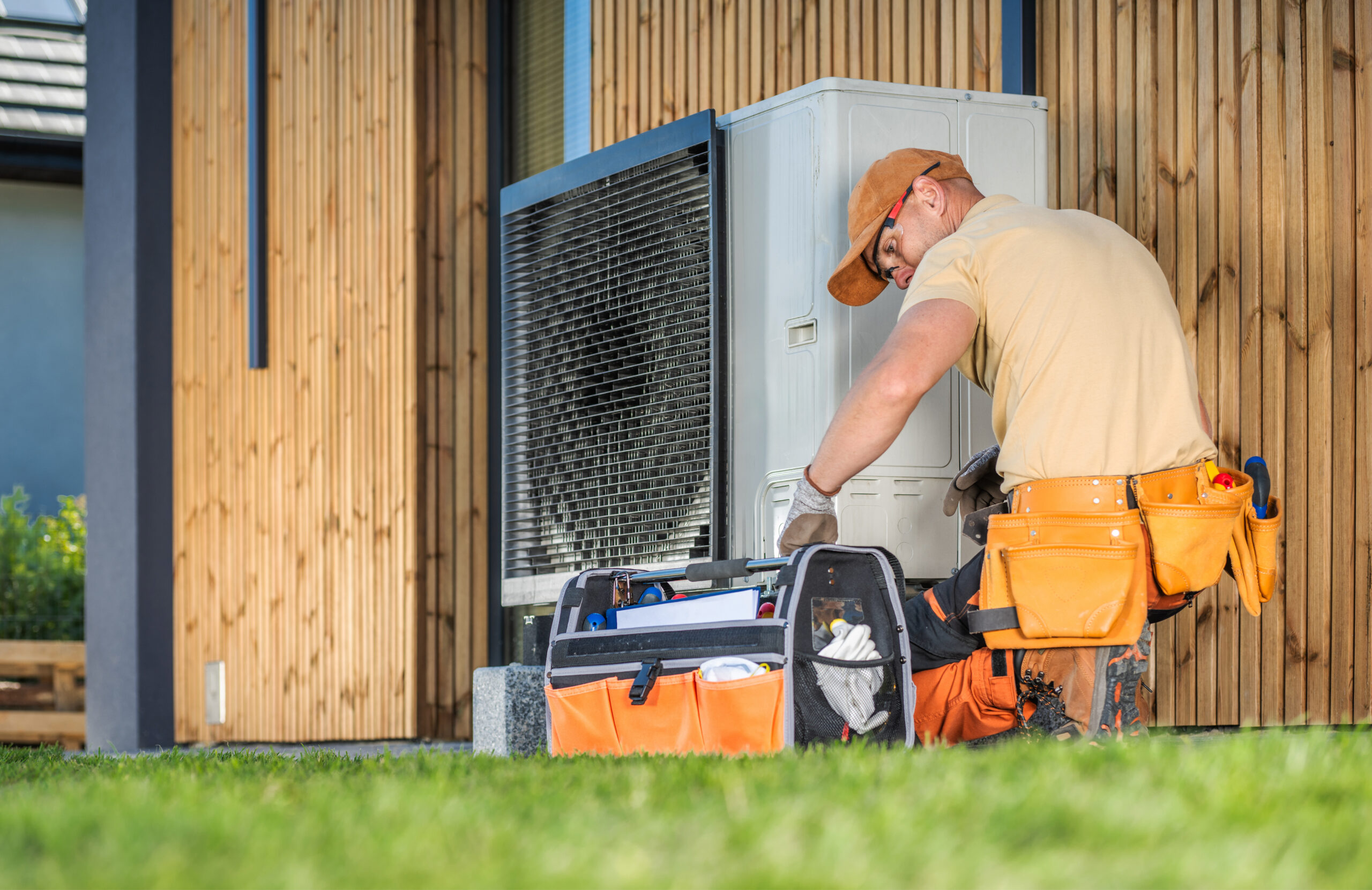 Wartung einer Wärmepumpe: Ein Installateur wartet eine Wärmepumpe an einem Einfamilienhaus.