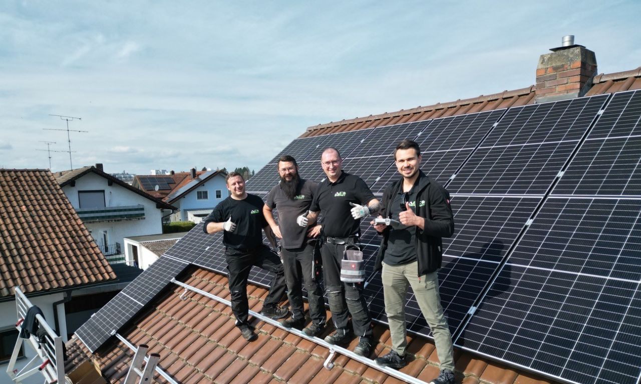 Vier Installateure von AF Energy machen lächelnd das Daumen-hoch-Zeichen bei der Modulmontage auf einem Kundendach