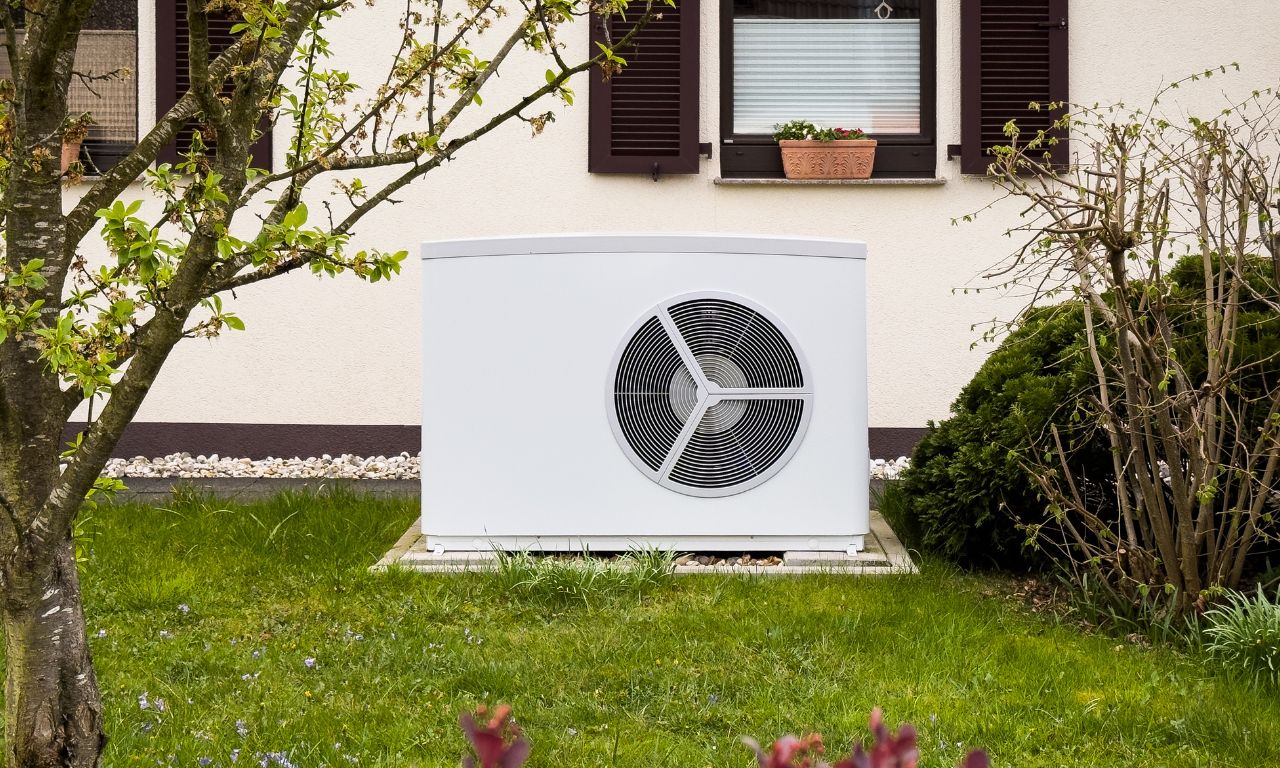 Weiße Wärmepumpe vor einem Einfamilienhaus